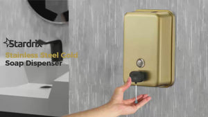 Hand using brushed gold bathroom soap dispenser
